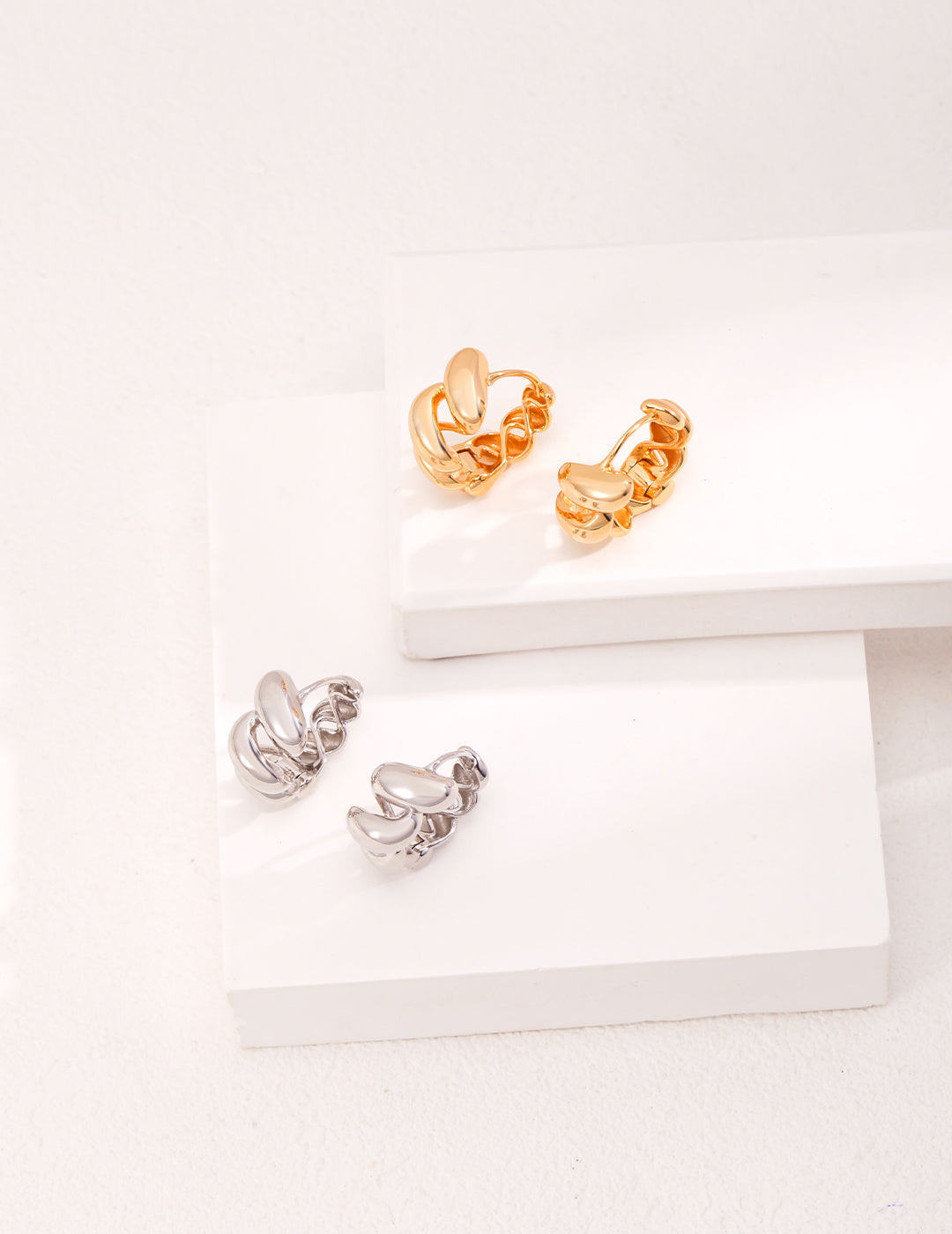 Pair of gold and silver hoop earrings on white background.
