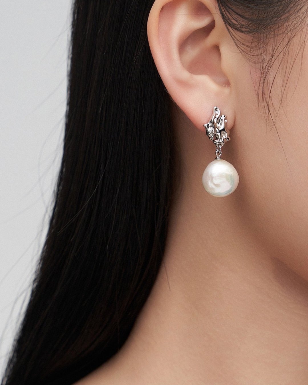 Close-up of a lady wearing exquisite silver baroque pearl earrings, emphasizing their cute and striking design.