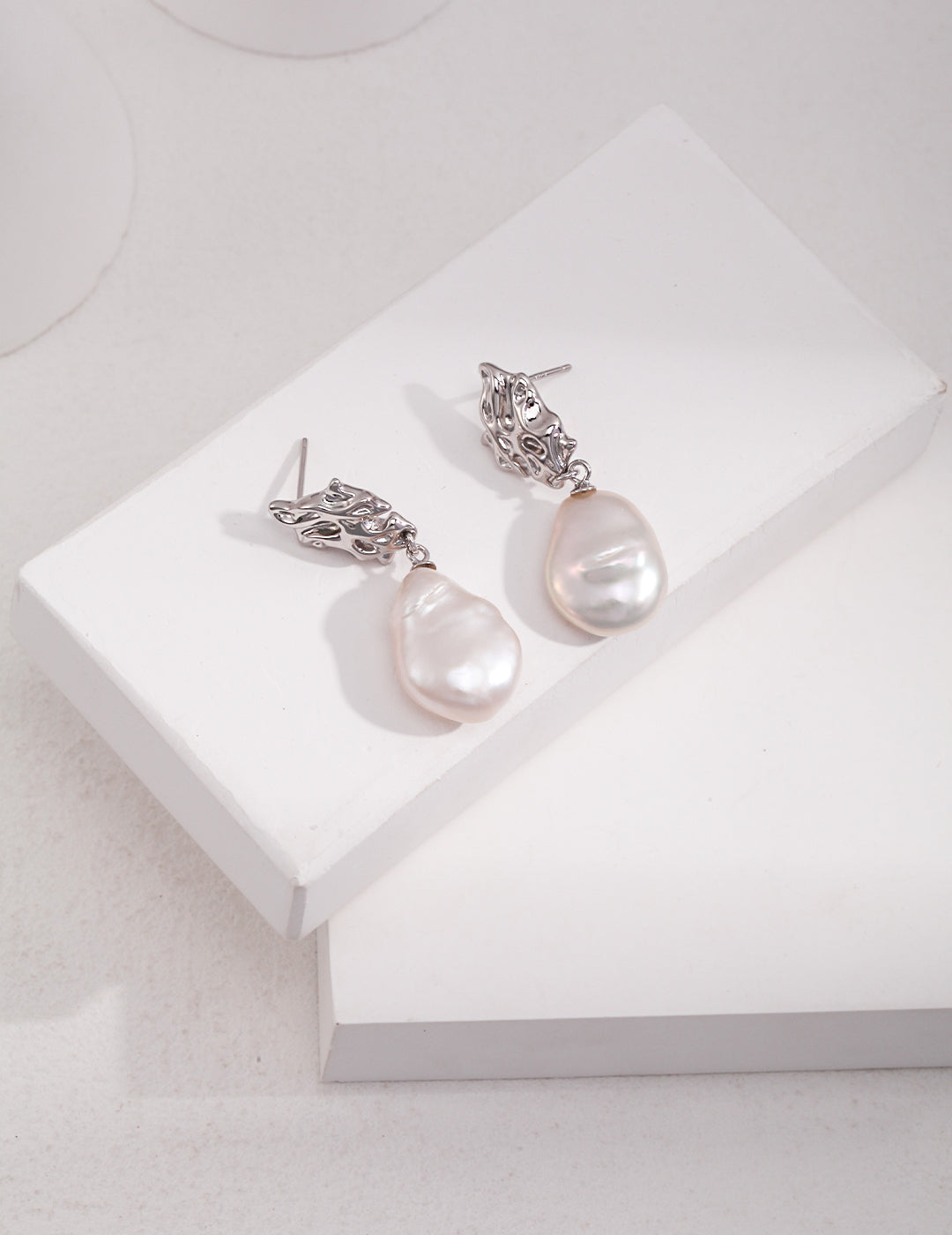 Silver baroque pearl earrings resting on a white box, showcasing their cute and aesthetic dreamy design.