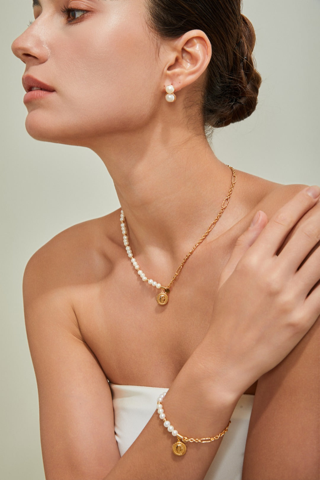 Elegant woman in a white dress, complemented by a stunning gold necklace, radiating beauty and sophistication.