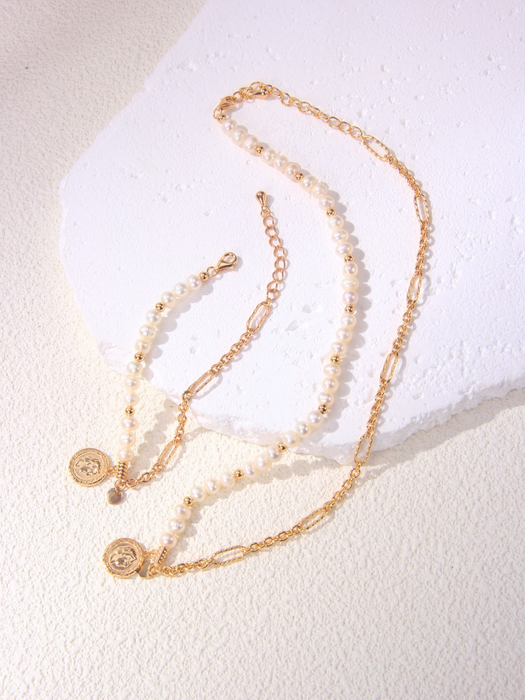 A stylish gold necklace with a coin charm and a matching bracelet, highlighting a chic and coordinated jewelry set.