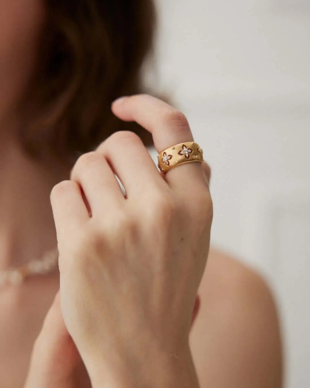 Close-up of a woman's hand displaying a gold ring featuring sparkly zirconia stones.