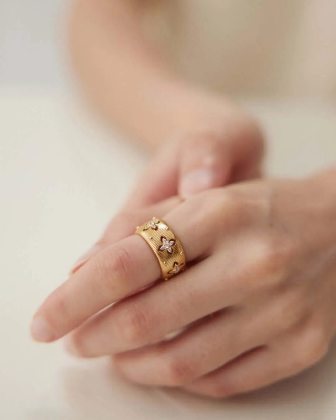 A detailed view of a woman's hand with a gold ring, emphasizing the ring's luster and the hand's graceful posture.