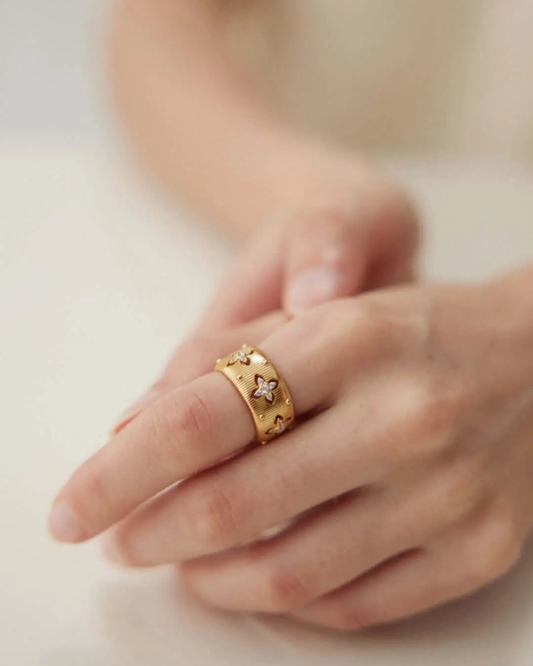 A detailed view of a woman's hand with a gold ring, emphasizing the ring's luster and the hand's graceful posture.