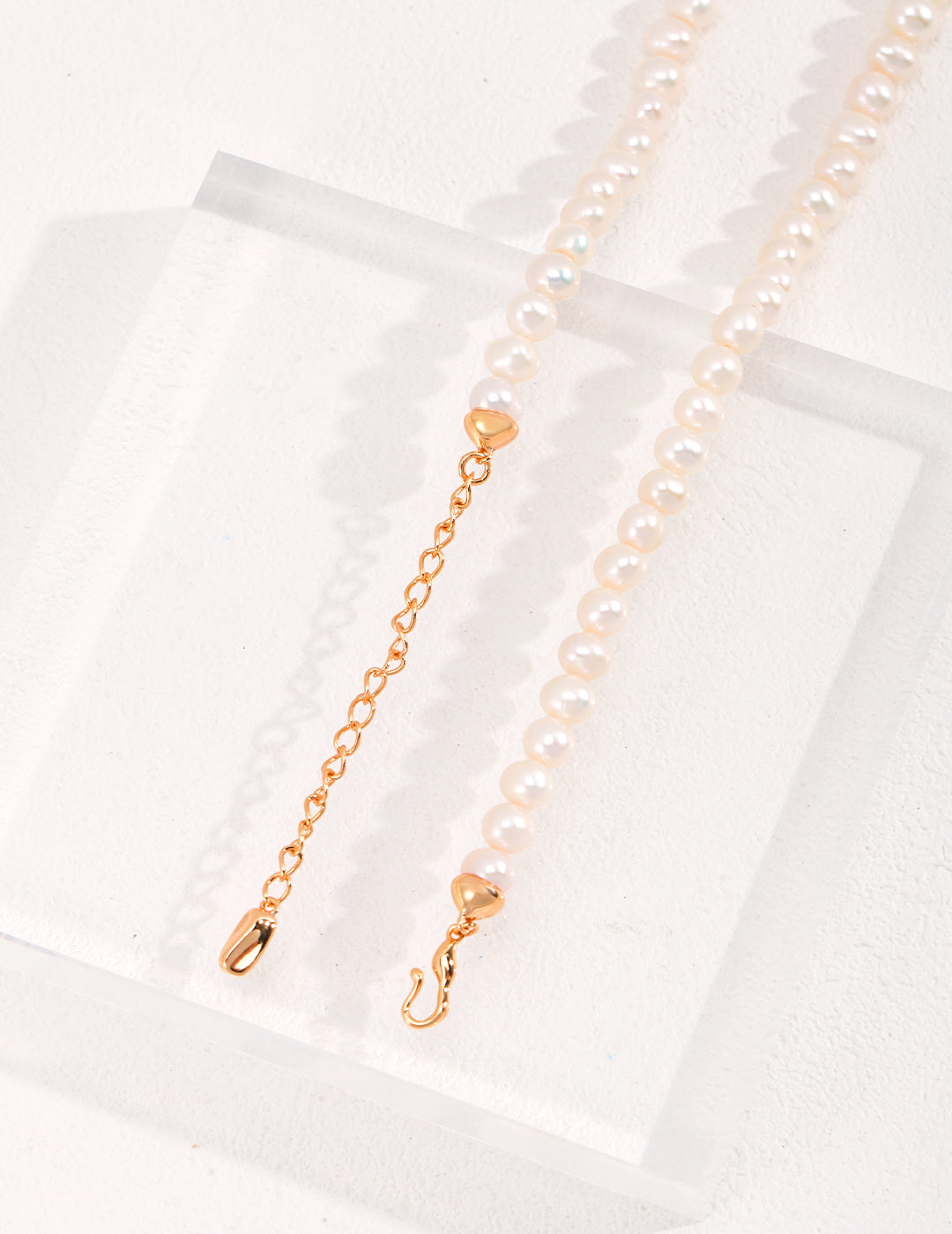 Shiny gold chain and elegant freshwater pearl necklace showcased.