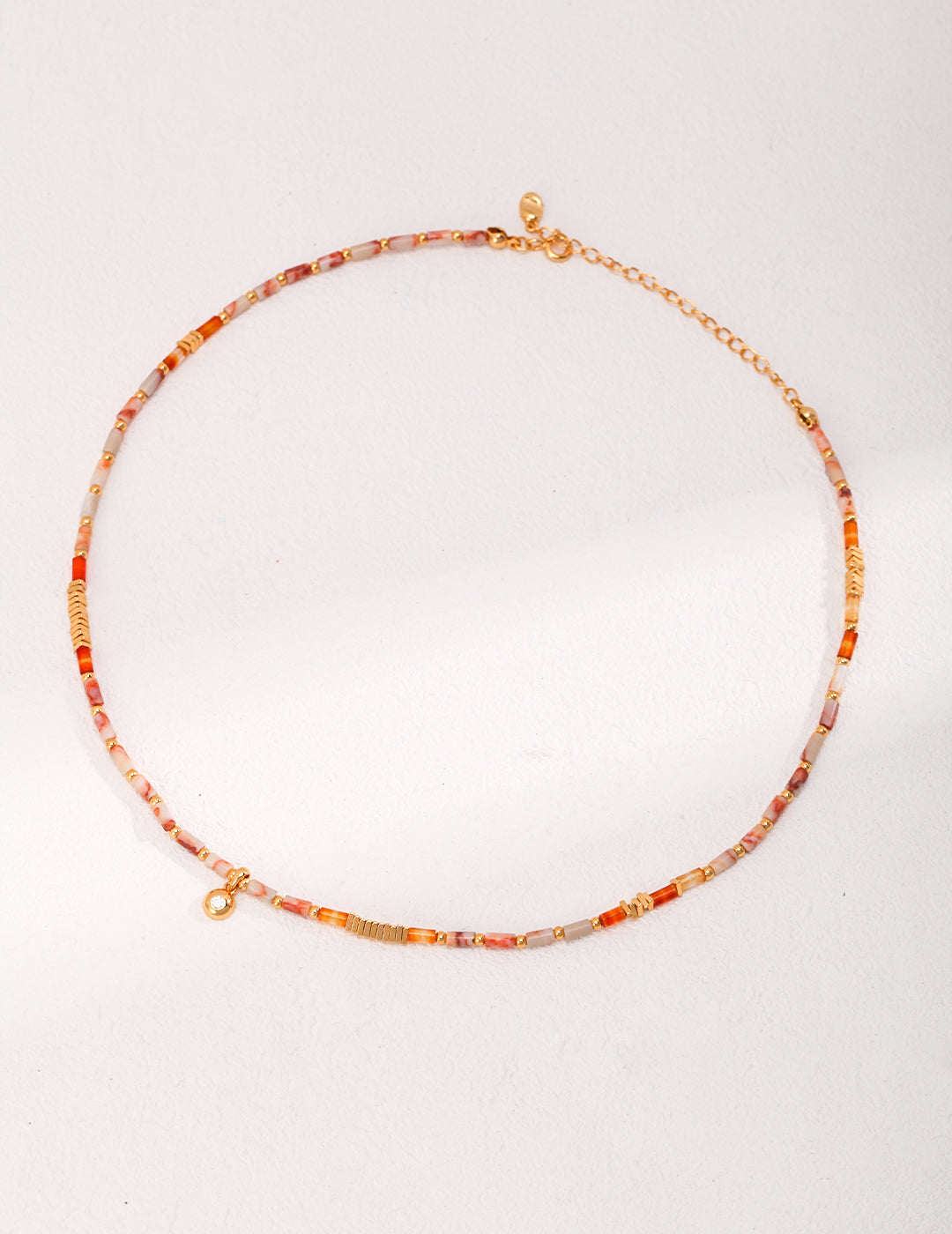 Eye-catching orange and gold necklace adorned with colorful gemstones.