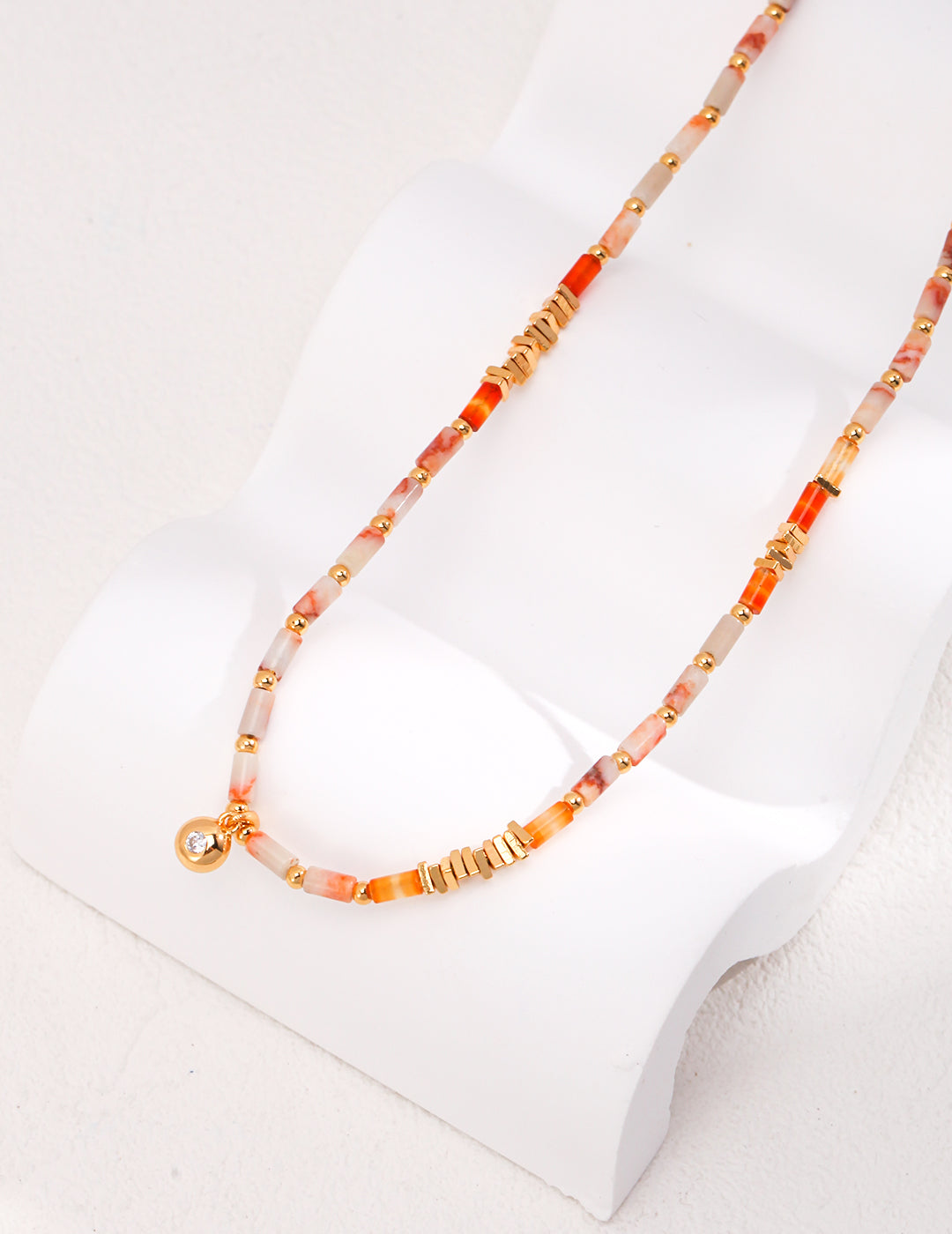 Vibrant necklace featuring orange, gold beads and gemstones on a white background.