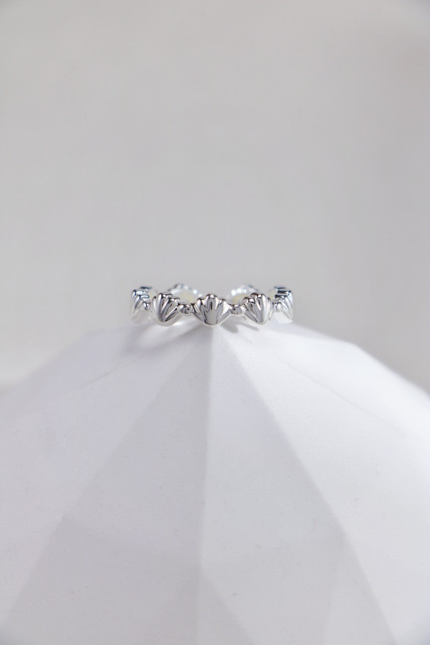 A stunning seashell inspired ring resting on pristine white marble, highlighting its exquisite design and shine.