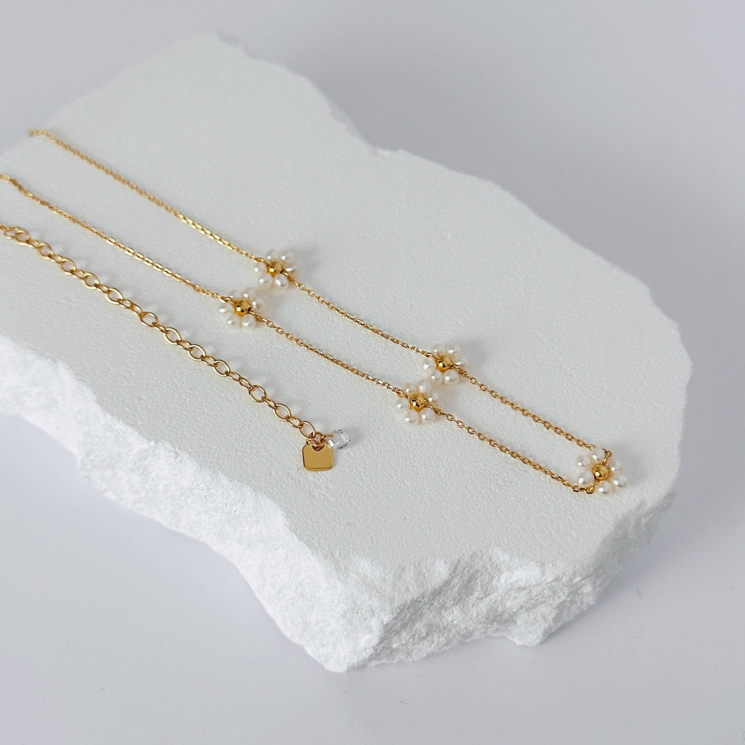 Chic gold chain necklace with a pearl and gold beads, highlighted by a graceful pearl petal accent.