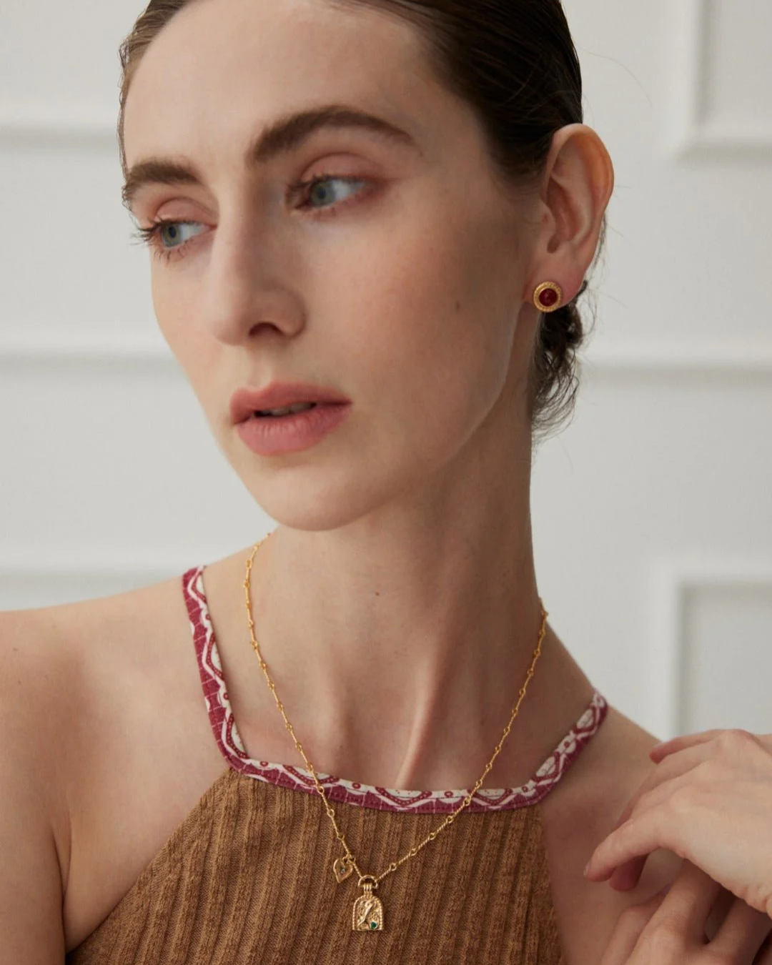 A woman displaying a beautiful gold necklace and earrings, highlighting her sophisticated fashion choice.