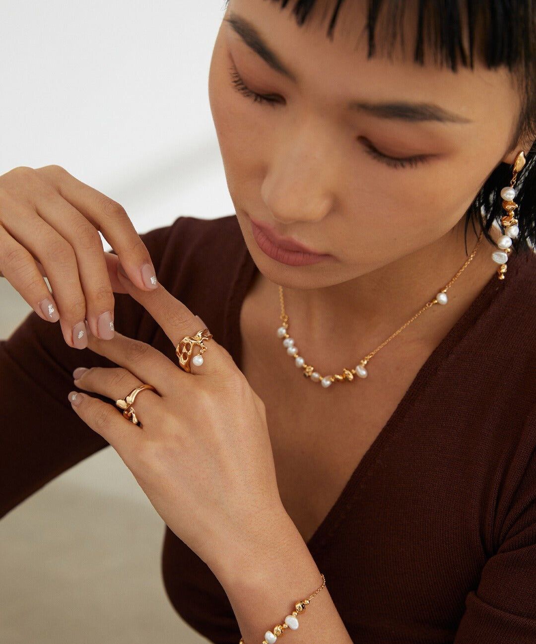 A stylish woman wearing a gold necklace and bracelet, adorned with gold plated freshwater pearl beads, showcasing her elegant taste.