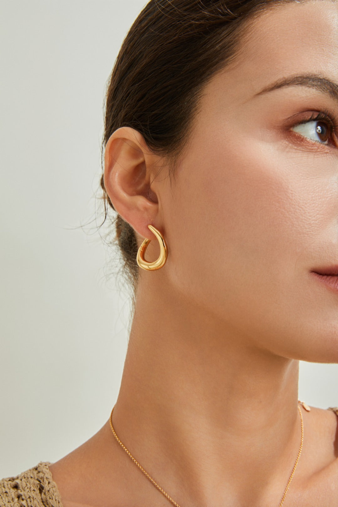 Beautiful gold earrings made from a single metal piece, emphasizing their sleek and minimalist aesthetic.