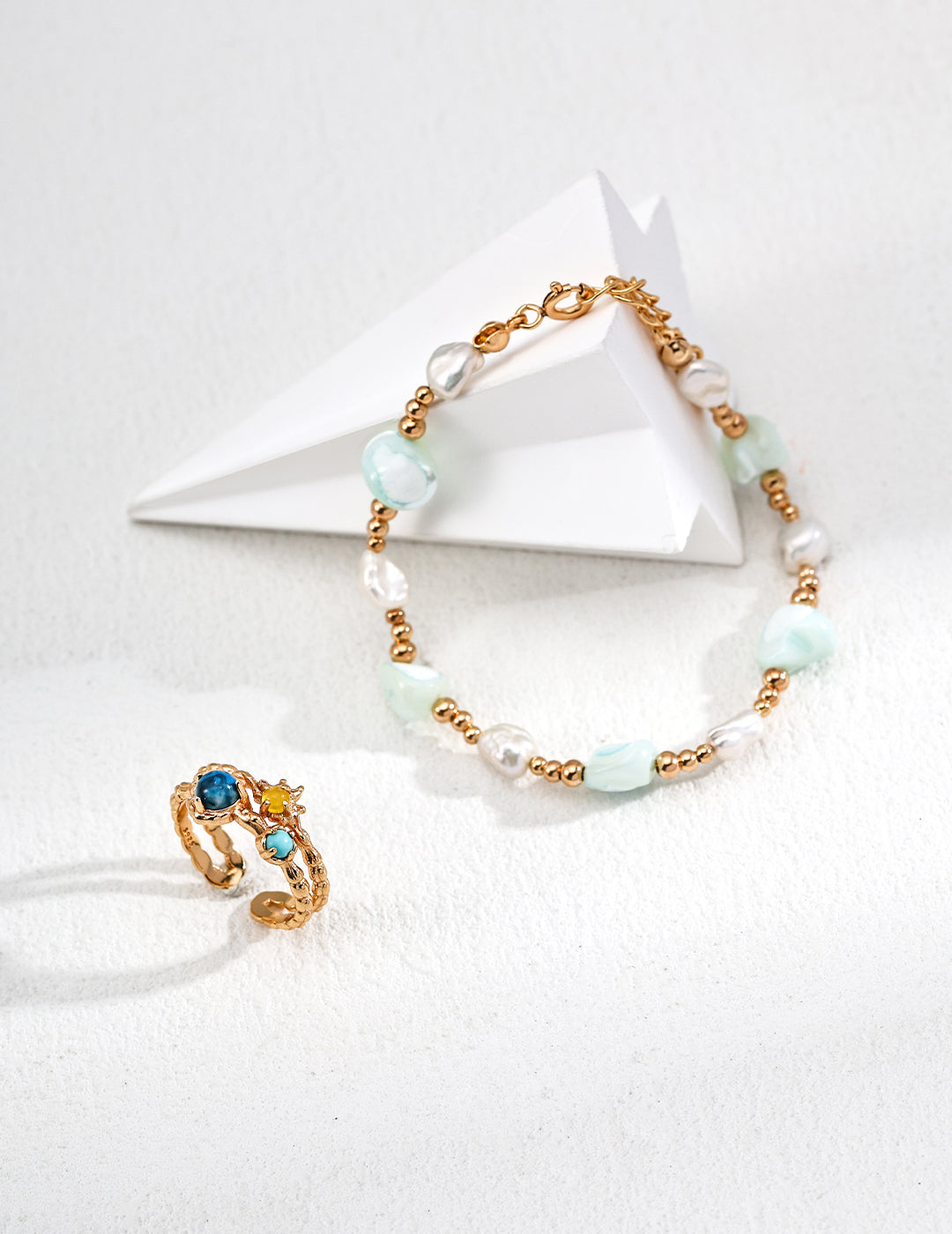 Gold chain bracelet and ring set, embellished with freeform shells and freshwater pearls for a chic look.