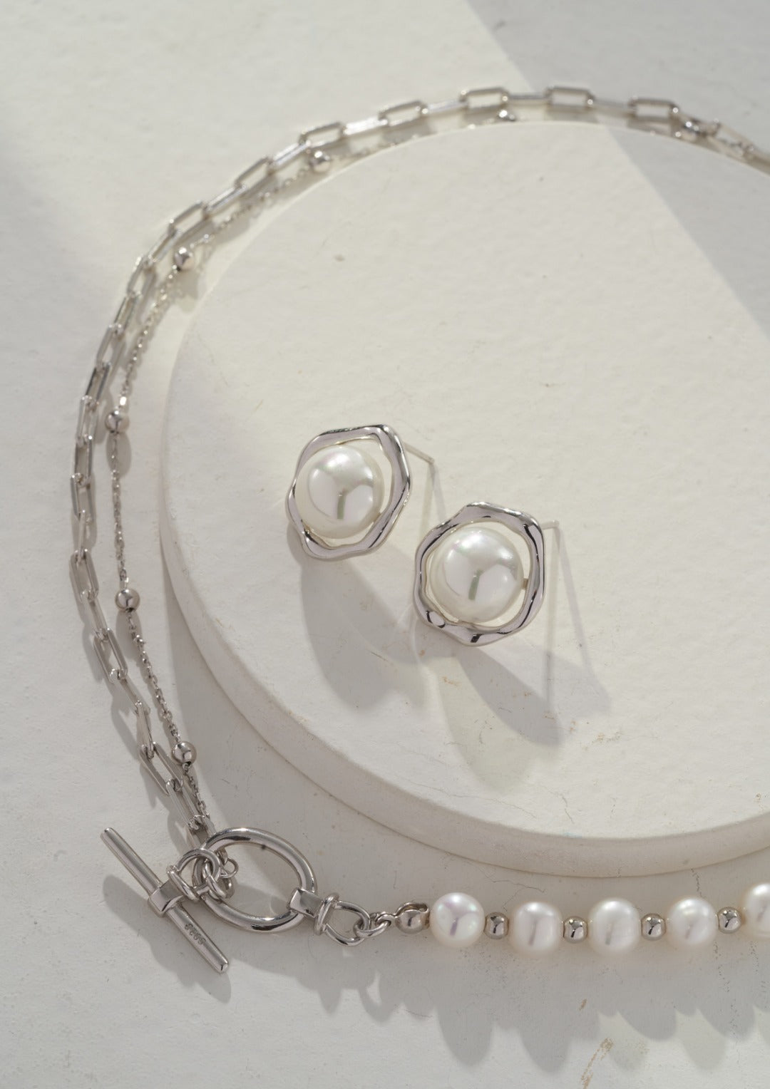 Elegant pearl necklace and earrings set, featuring a combination of pearls and a silver chain design.