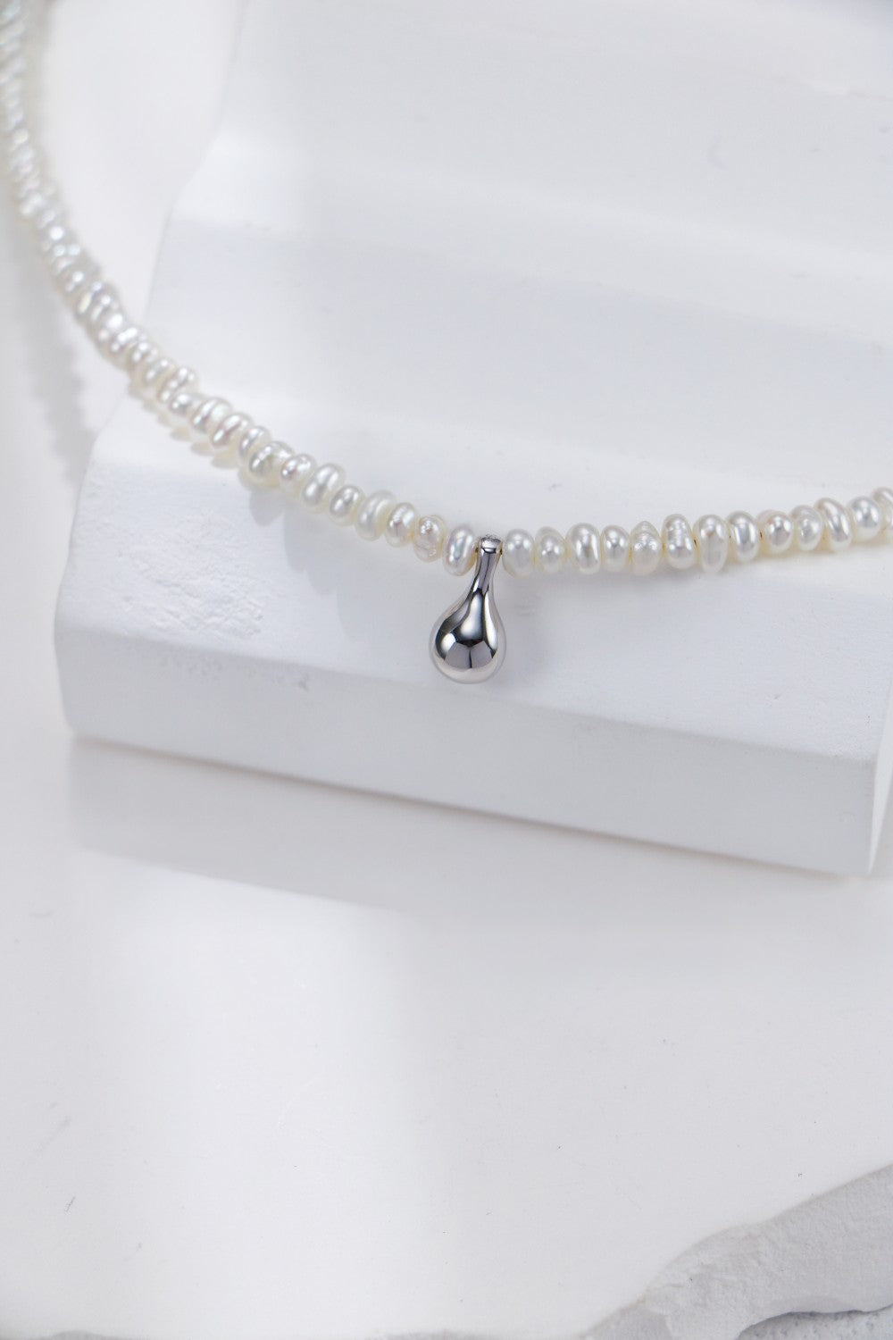 A stunning white pearl necklace adorned with a silver heart charm, ideal for special occasions or everyday elegance.