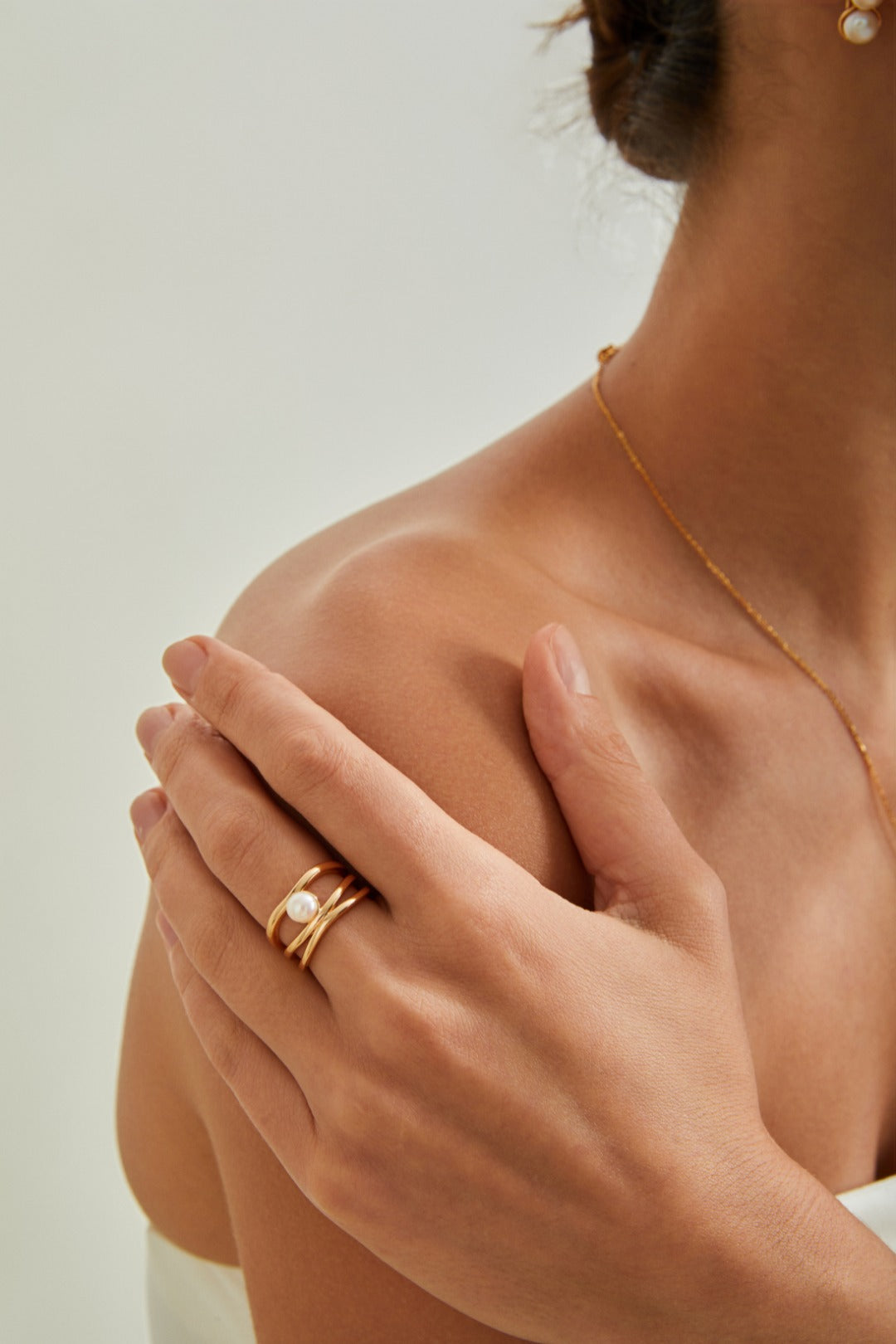 Close-up of a woman with a gold ring resting on her shoulder, emphasizing her chic and sophisticated look.