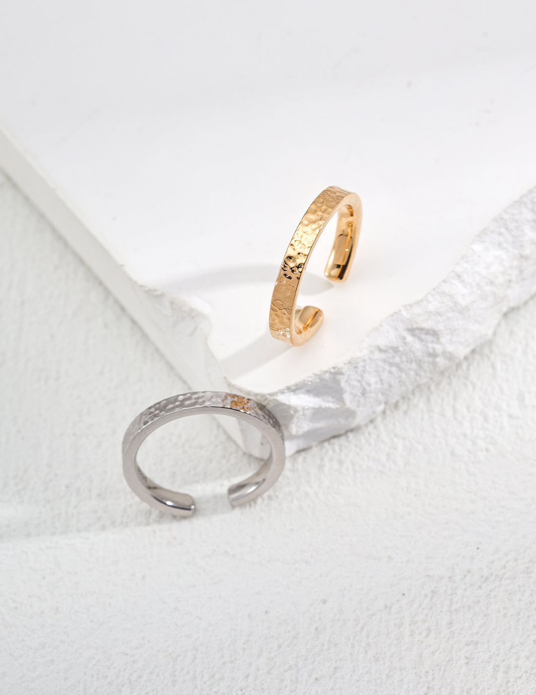A pair of stylish gold and silver rings displayed on a white surface, highlighting their modern elegance and craftsmanship.