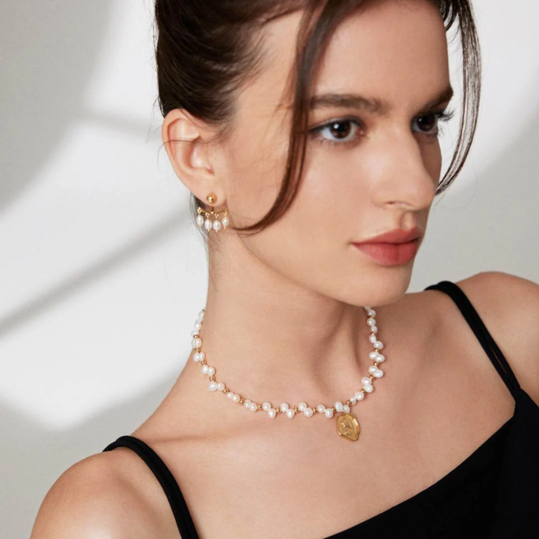 Elegant woman displaying a beautiful necklace and earrings, enhancing her graceful appearance.