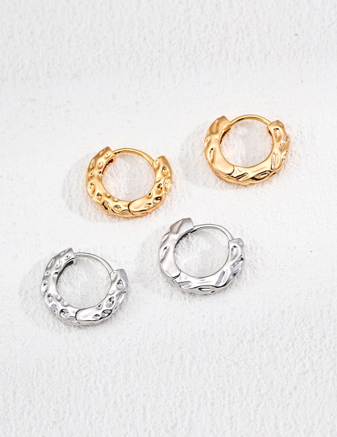 Two set of gold and silver hoop earrings on a white background.