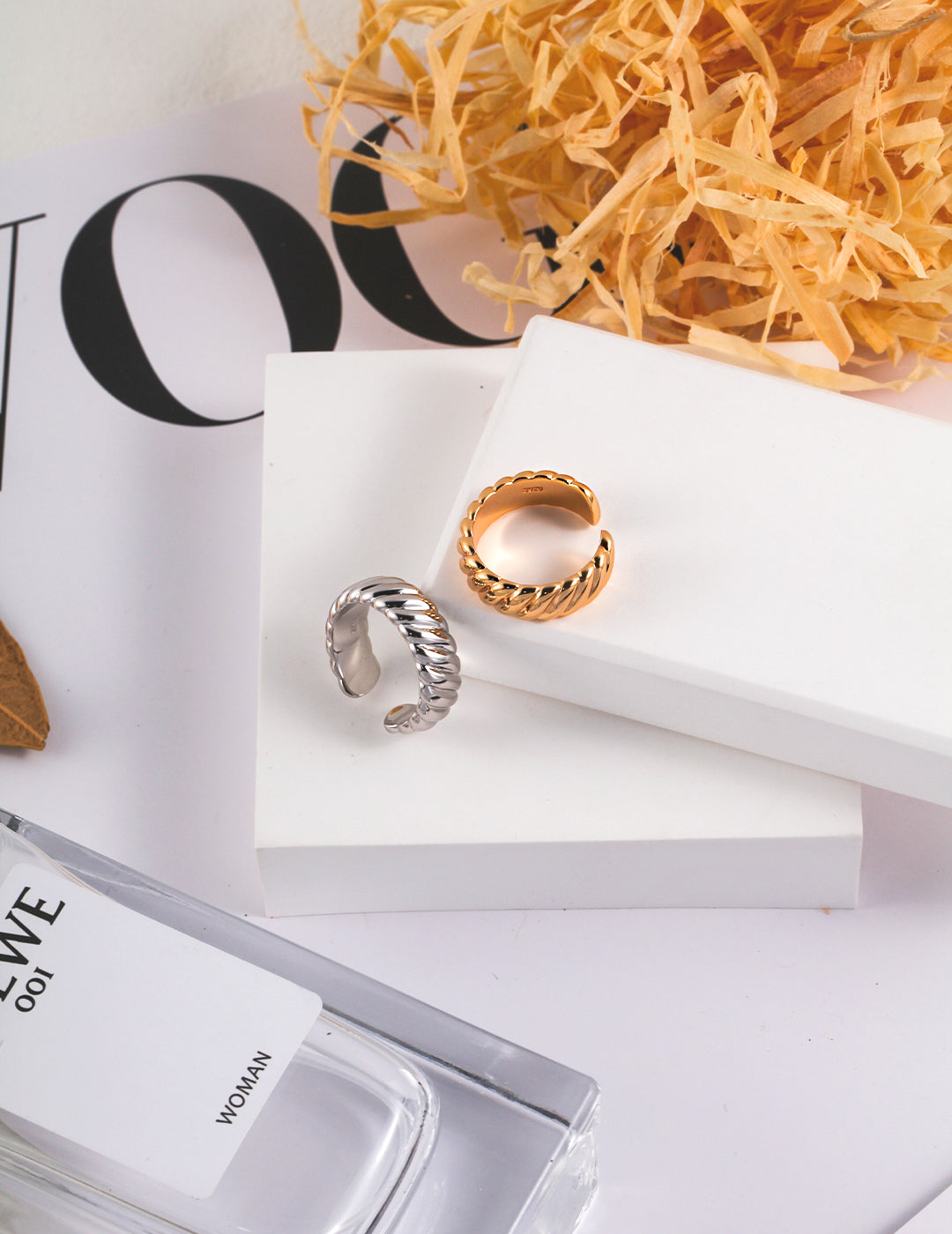 Two rings (one silver and one gold) and a bottle of perfume on a table - a symbol of elegance and beauty.