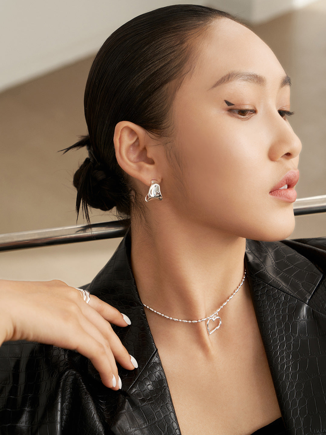 Fashionable woman wearing black leather jacket and silver earrings.