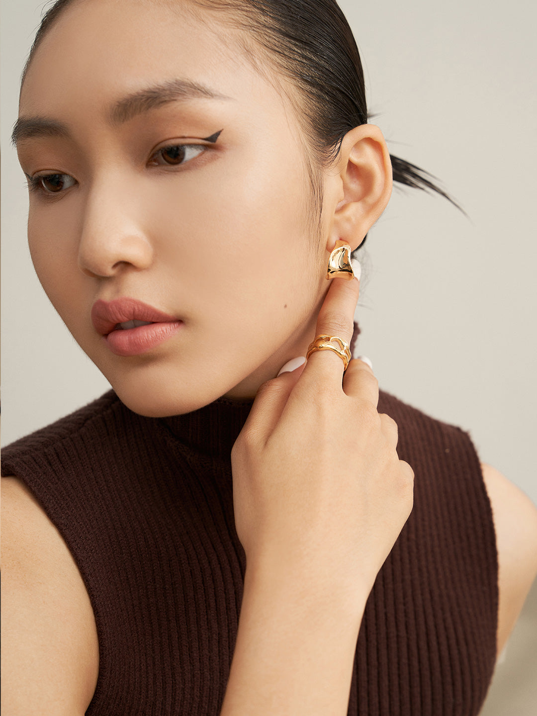 Fashionable woman in burgundy top and gold hoops.