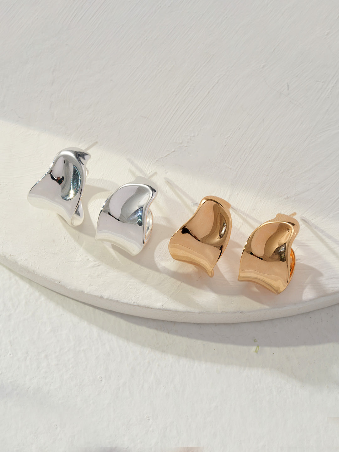 Two pairs of elegant silver and gold earrings, perfect for adding a touch of glamour to any outfit.