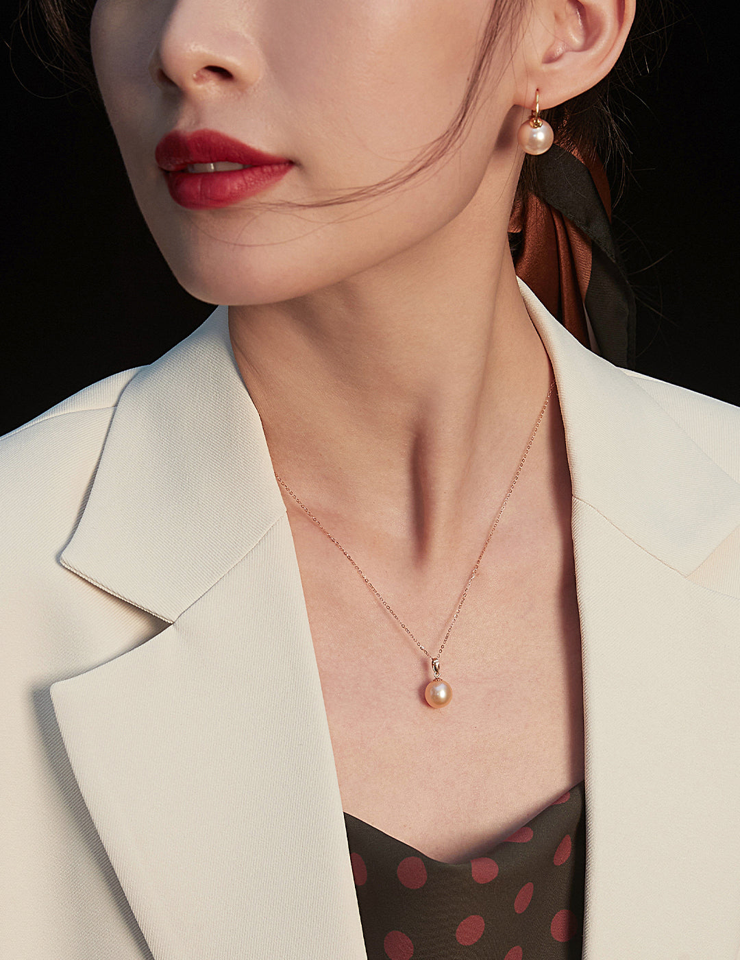 A woman dressed in a white blazer complements her look with a beautiful rose gold freshwater pearl necklace, embodying grace.