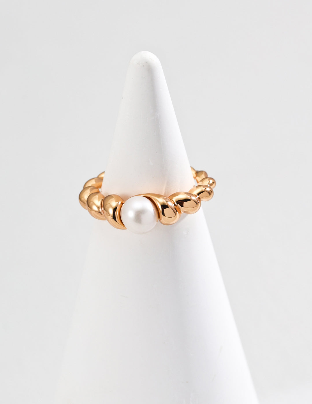 Elegant gold ring adorned with a beautiful pearl on top, radiating luxury and classic style in a simple design.