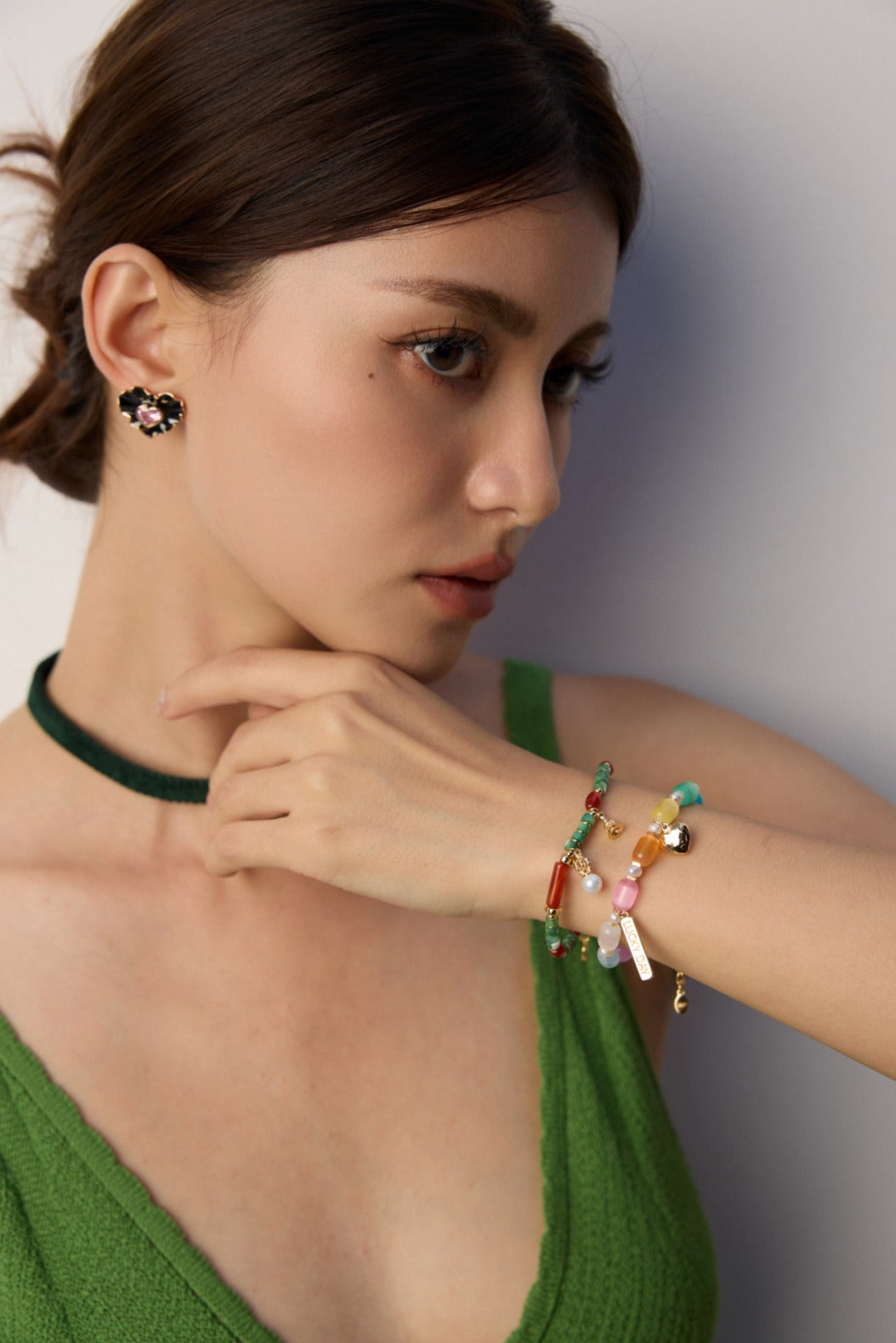 A woman dressed in green sports a colorful cat's eye bracelet, adding a playful touch to her outfit.