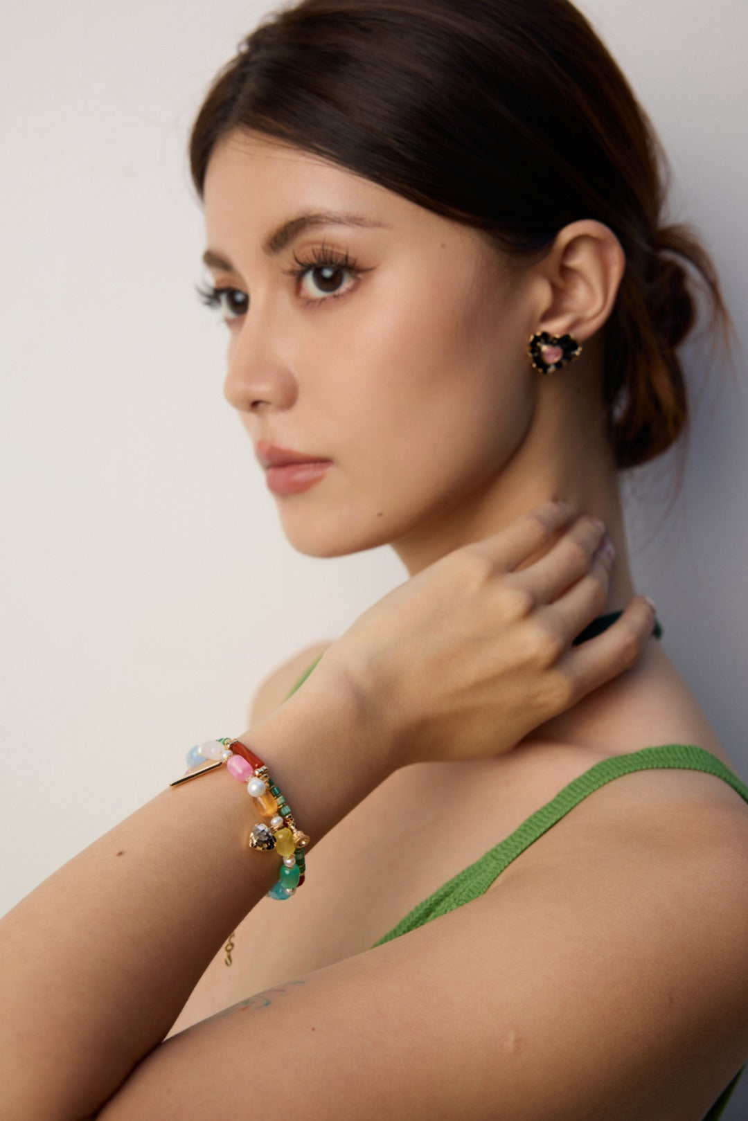 A woman in a green dress wearing a rainbow-colored bracelet on her wrist.