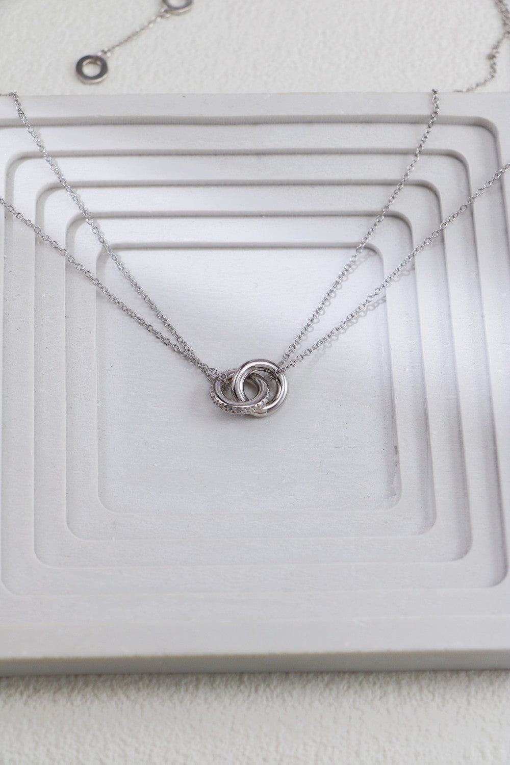A delicate silver necklace featuring a simple, elegant circle pendant.
