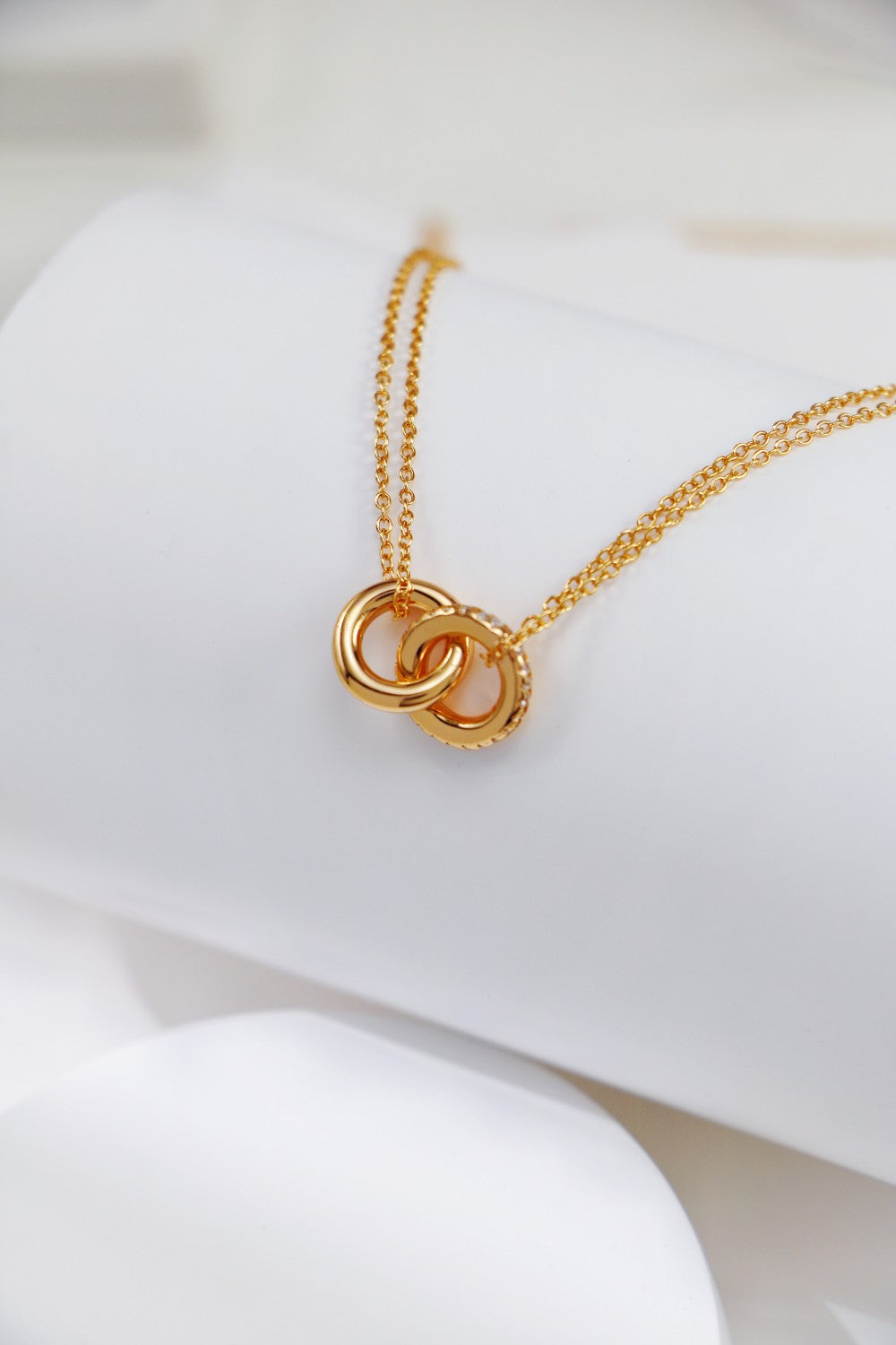 An exquisite gold necklace adorned with two intertwined rings, capturing the essence of harmony and elegance.