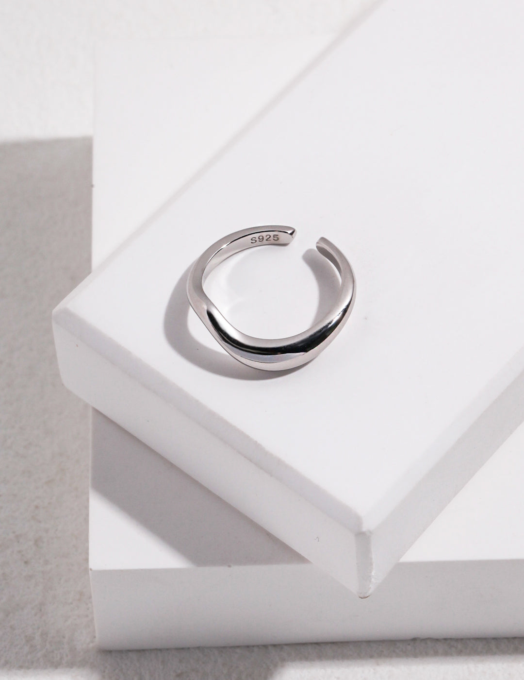 Minimalist silver ring on top of a white box.
