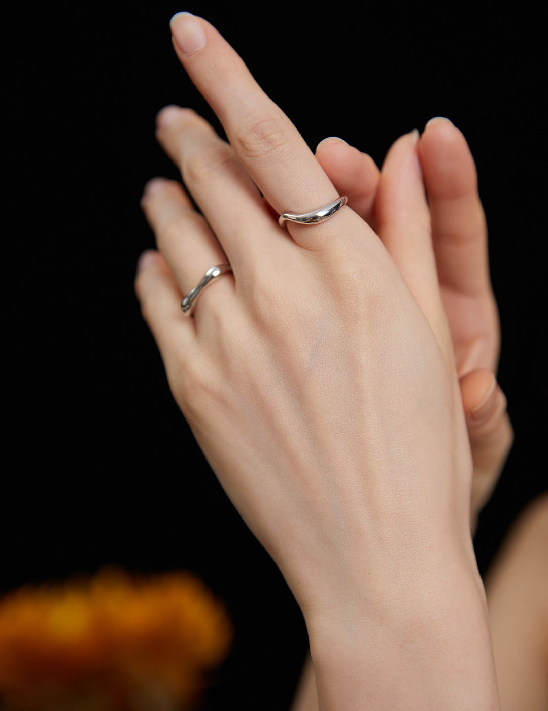 A woman wearing simple silver rings on her hands, showcasing elegance and style.