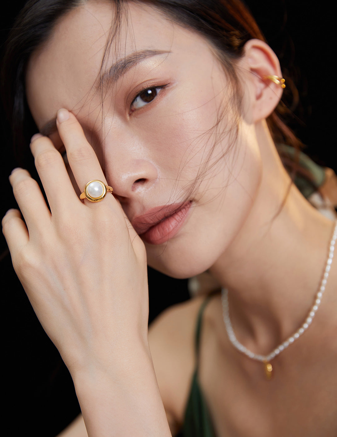 Elegant lady flaunting gold ring and pearl necklace.