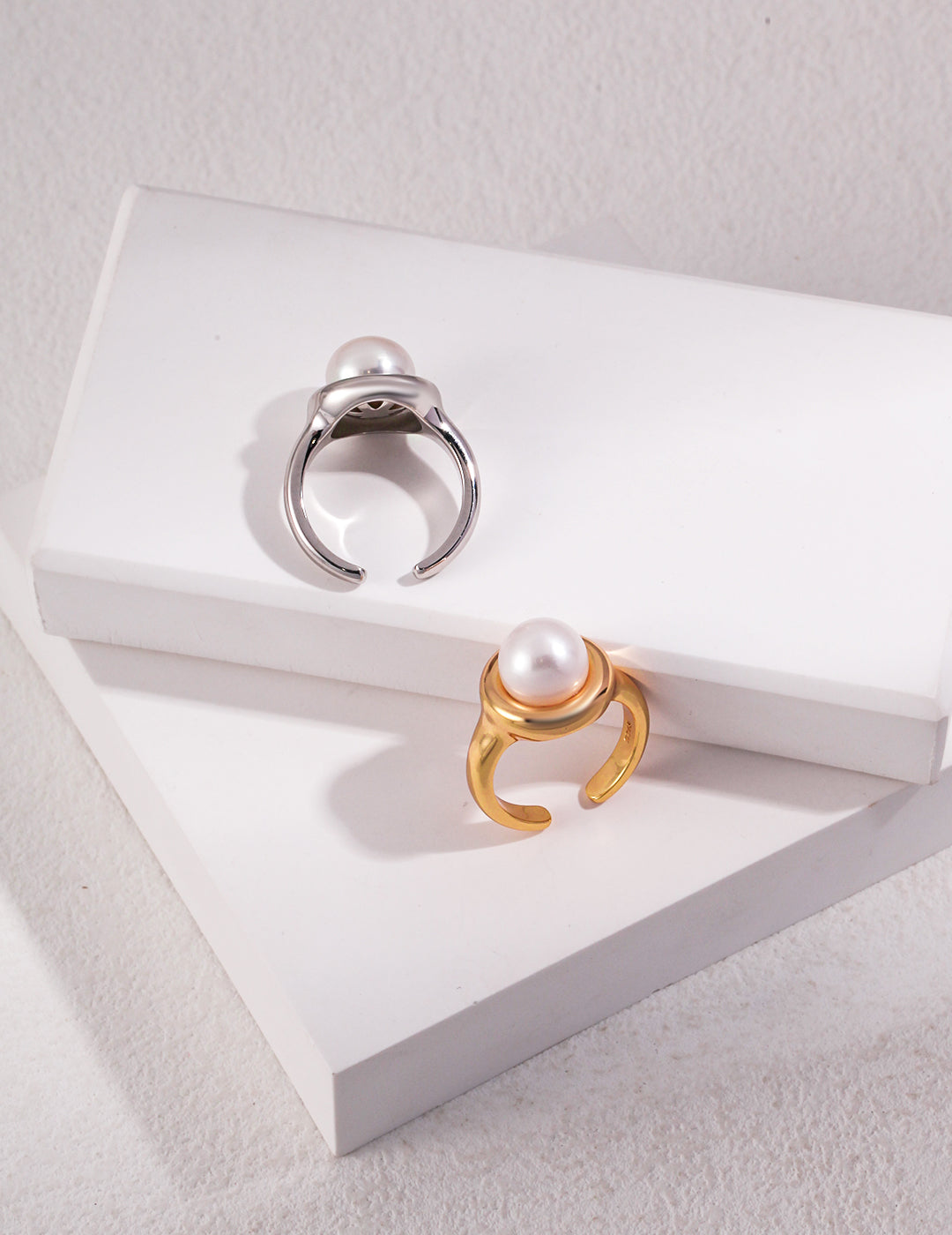 Freshwater pearl silver and gold rings on white box.