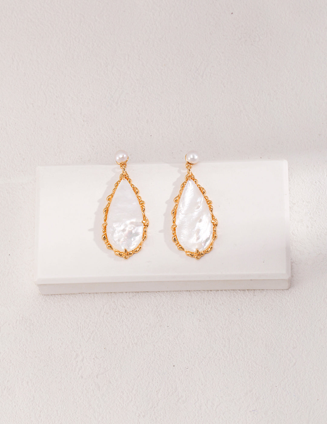 Elegant gold plated pearl dangle earrings displayed on white background