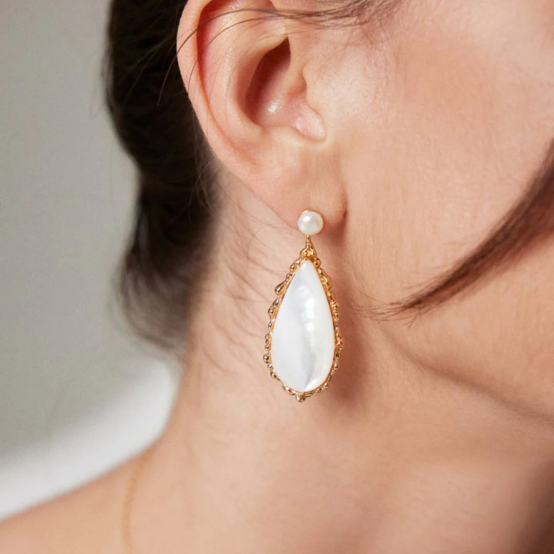 Elegant woman wearing pearl earrings, highlighting her refined style and grace.