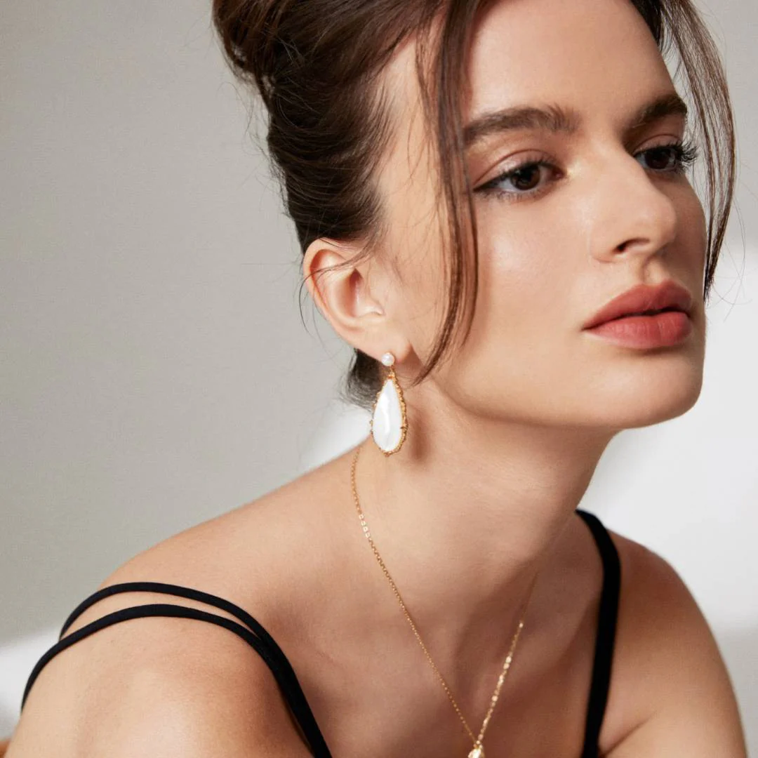 A stylish woman in a black bra top and gold earrings, radiating elegance and confidence.