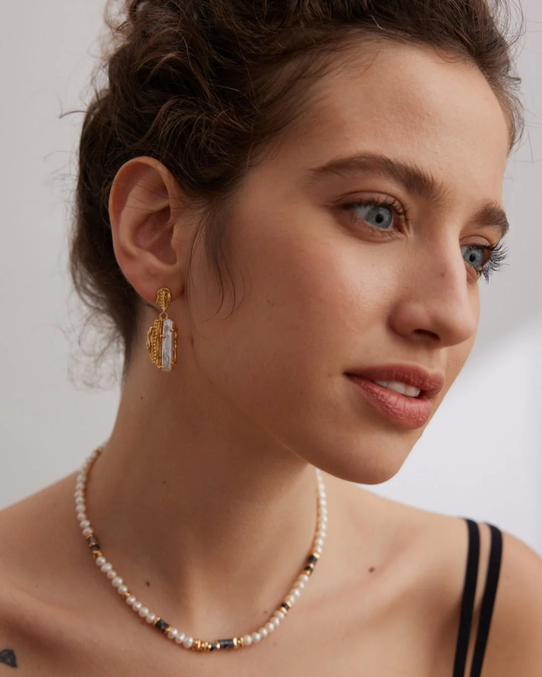 A woman adorned with a Labradorite pearl necklace and earrings, highlighting her sophisticated style and jewelry choice.