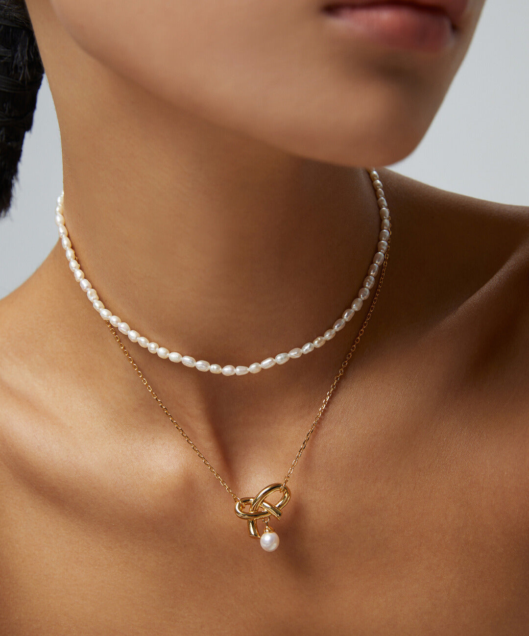 Woman adorned with gold necklace and rice pearl.
