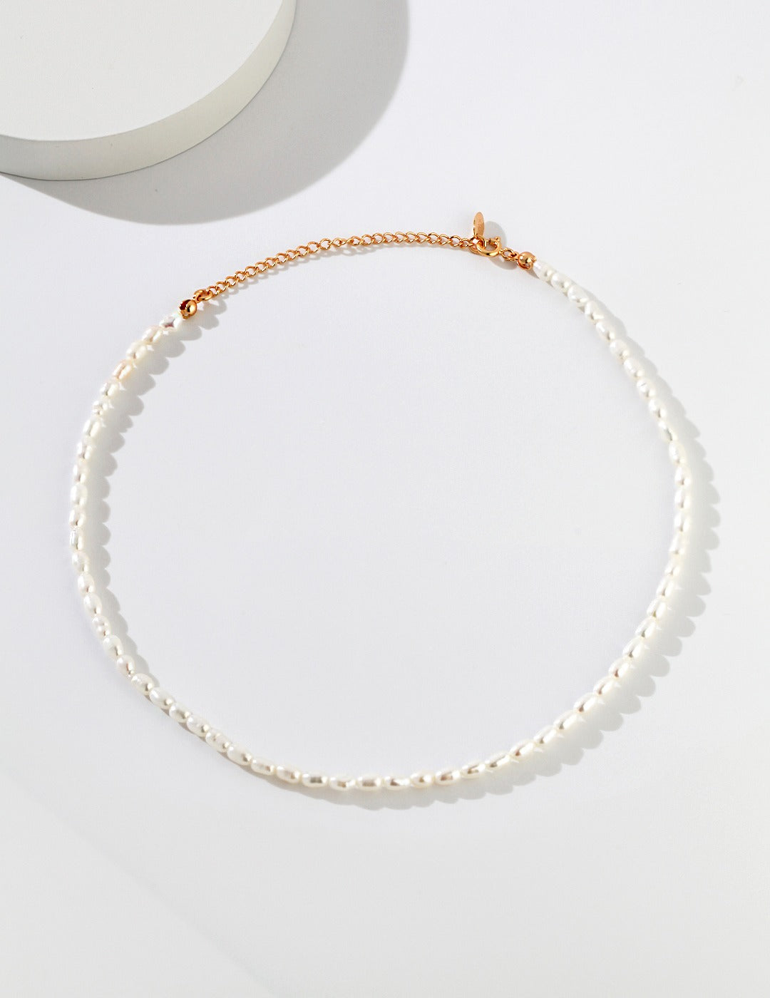 Gold chain necklace with white rice pearl pendant.