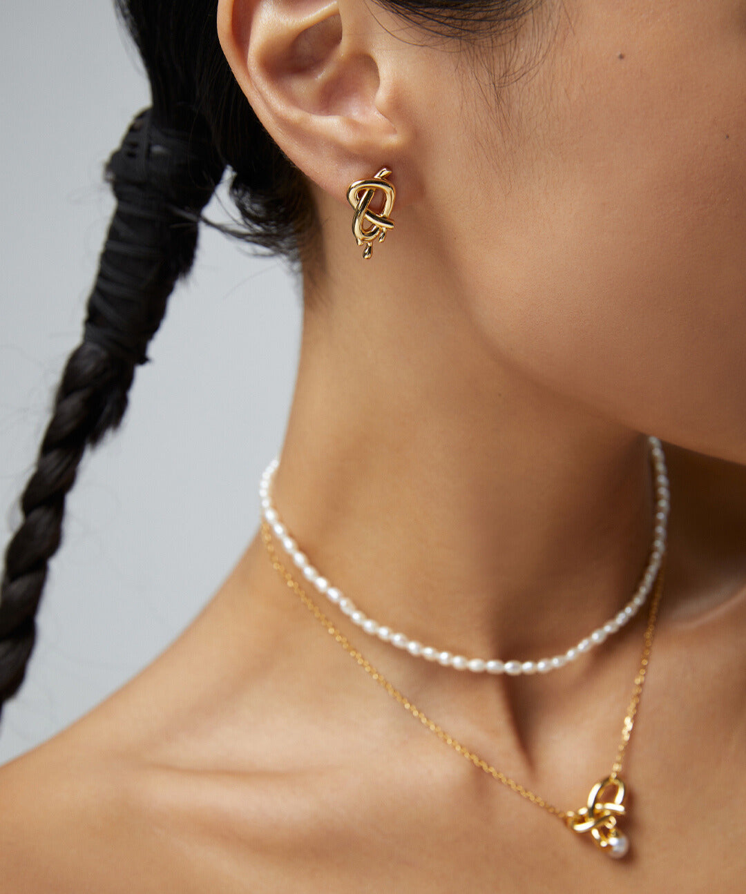 Elegant woman accessorized with gold necklace, earrings, and layered necklaces.