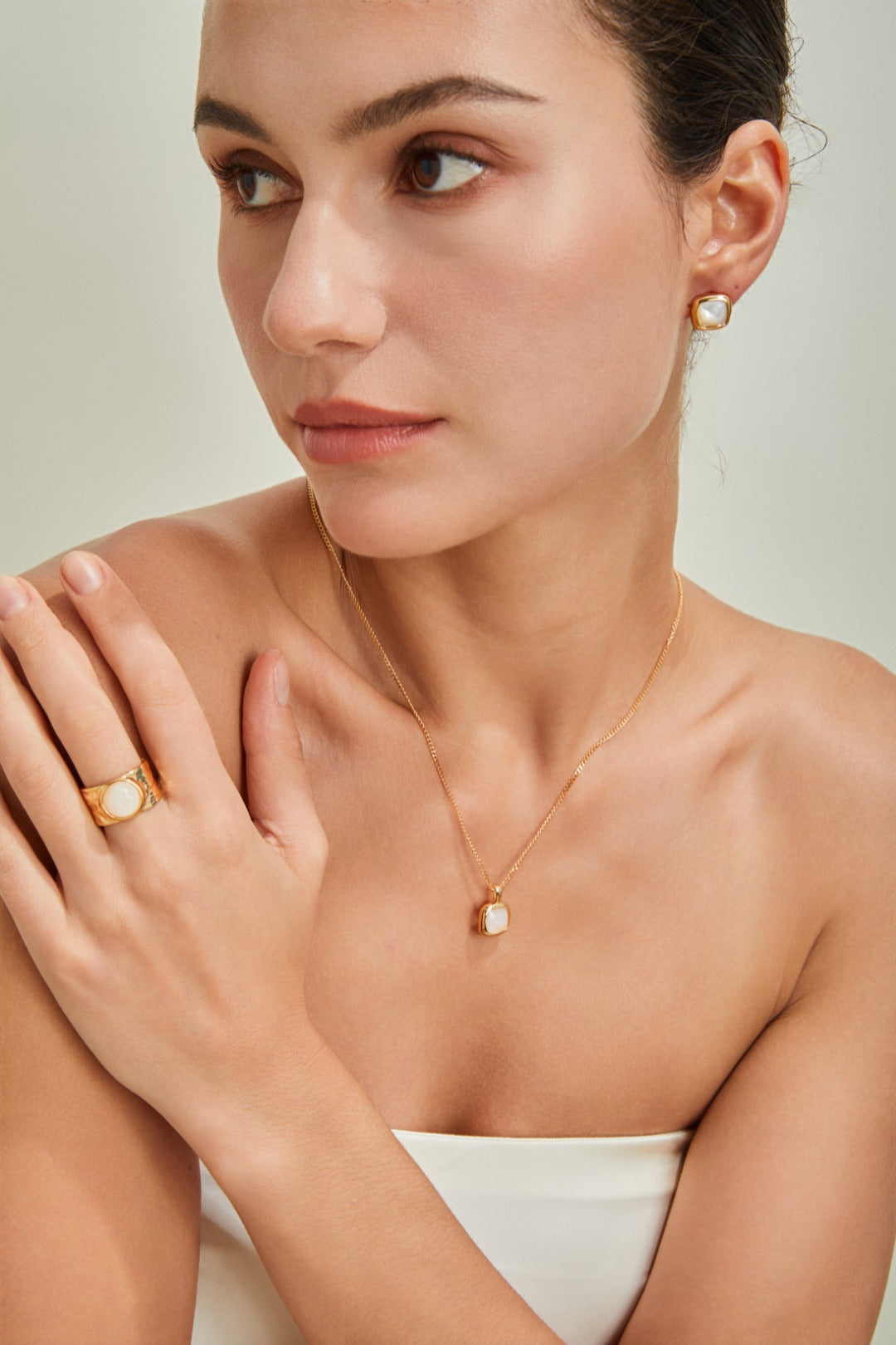 Stylish woman dressed in a white top, complemented by shimmering gold jewelry that enhances her look.
