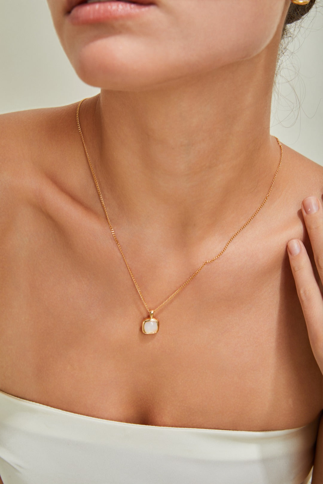 A woman dressed in a white top, complemented by a beautiful gold necklace, radiating luxury and grace.