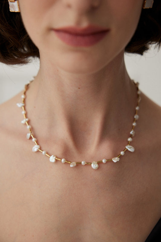 A woman adorned with a pearl necklace and earrings, combining baroque and freshwater pearls for a sophisticated, feminine appearance.