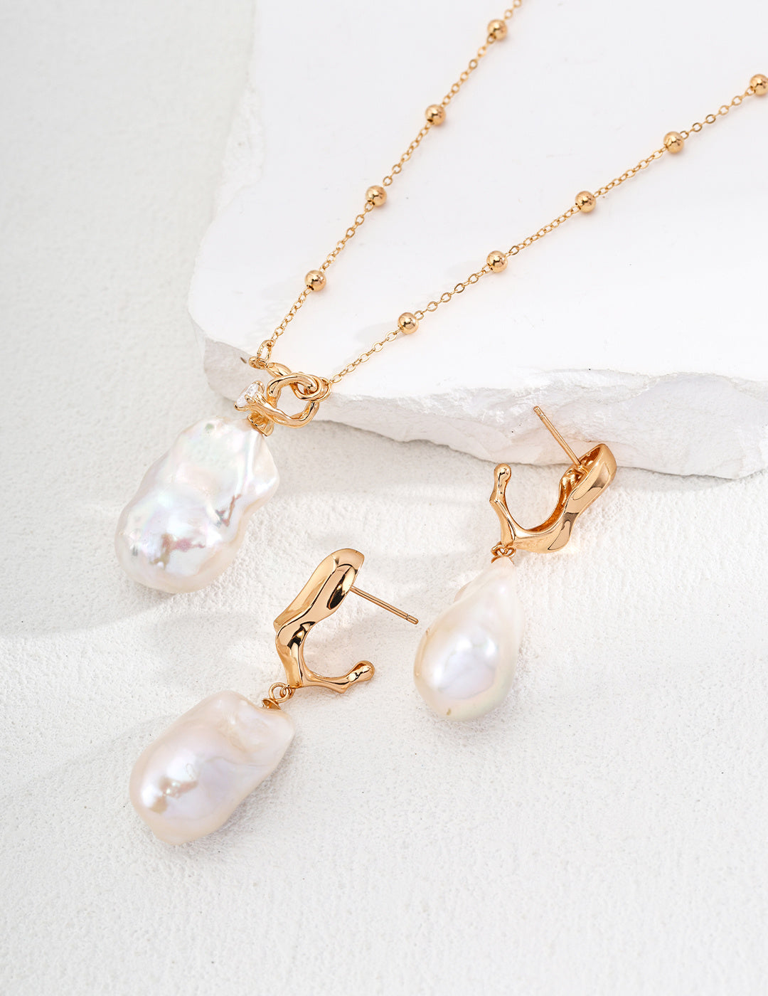 A white pearl necklace and matching earrings made of freshwater pearls displayed elegantly on a white surface.