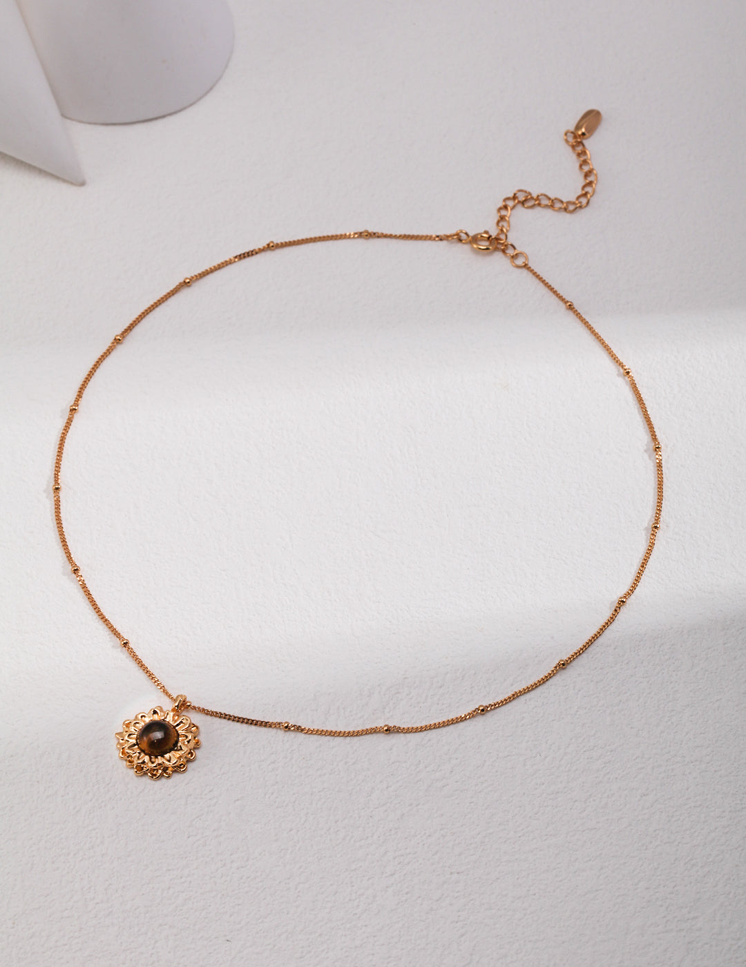 Dainty gold necklace with tiger's eye floral pendant.