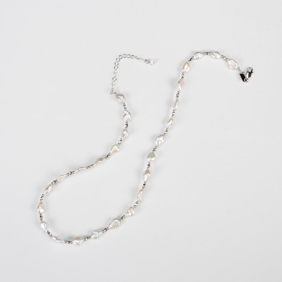 Close-up of a necklace with lustrous baroque white pearls and silver beads, emphasizing its delicate and feminine style.